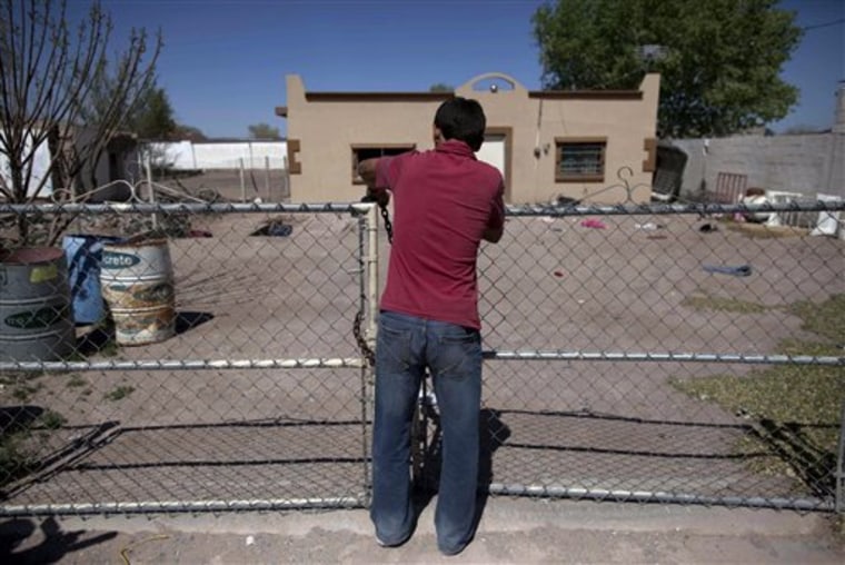 In this photo taken April 7, 2010, Christian, 14, locks the front yard door of his house while, accompanied by his family, leaving El Porvenir, Valle de Juarez, northern Mexico. Hundreds of families are fleeing the cotton-farming towns of the Juarez Valley, a stretch of border 50 miles east of Ciudad Juarez. In a new strategy, Mexican drug cartels seeking to minimize interference with their operations are using terror to empty the entire area. (AP Photo/Guillermo Arias)